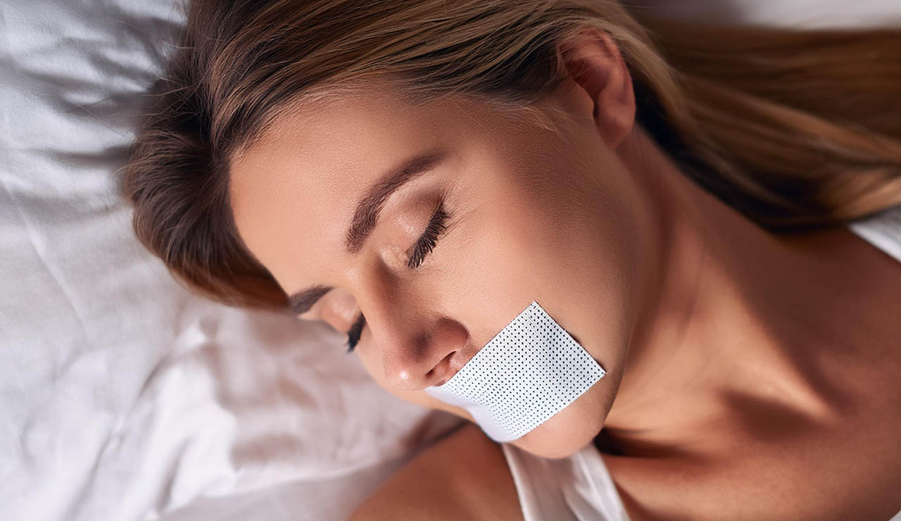 Mujer con cinta en la boca haciendo taping bucal