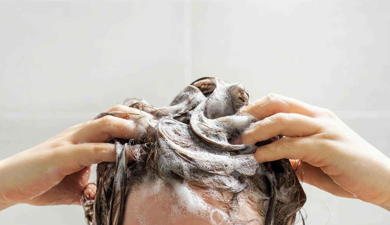 Persona lavándose la cabeza con champú