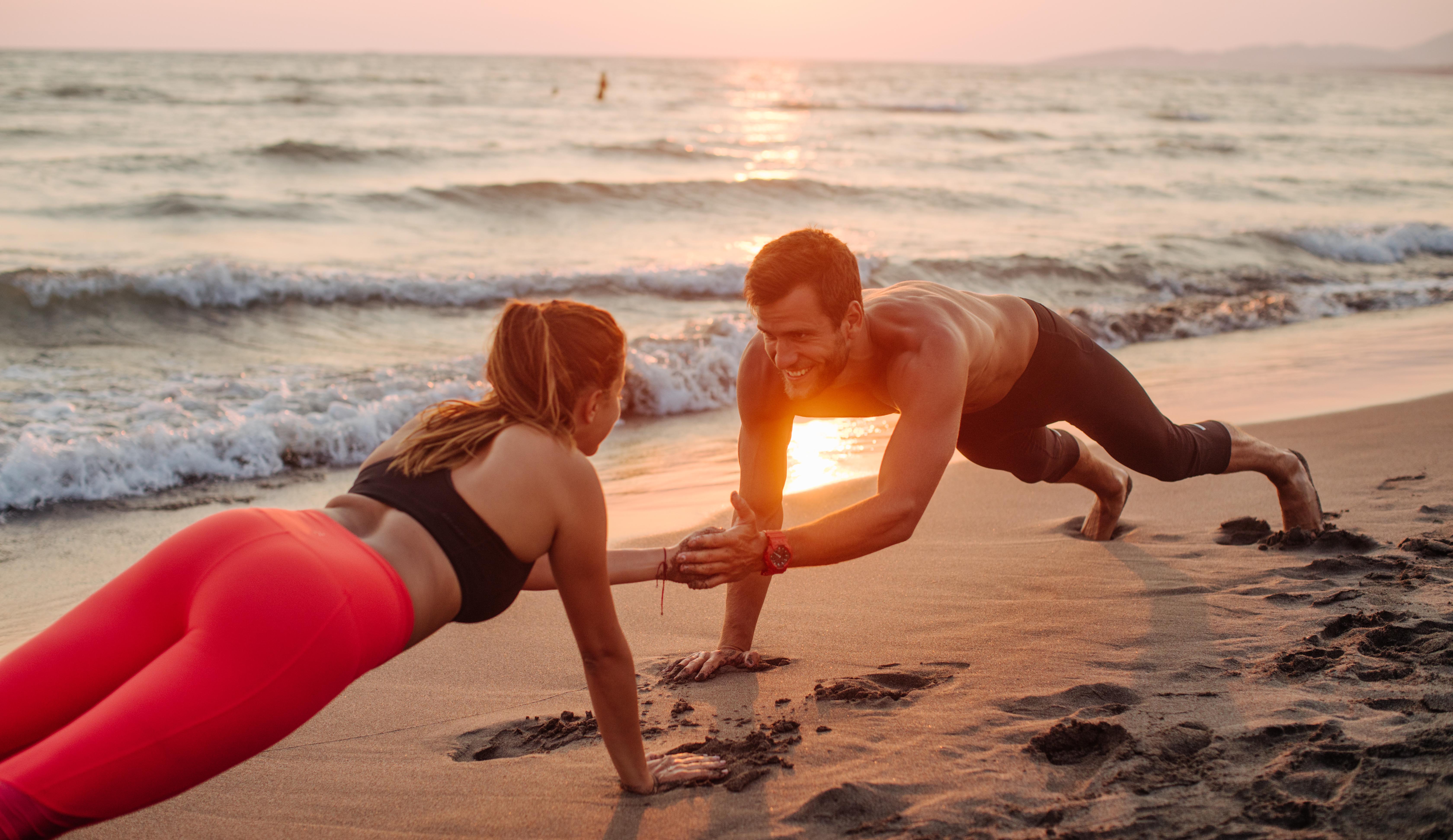 pareja practicando ejercicio en la playa