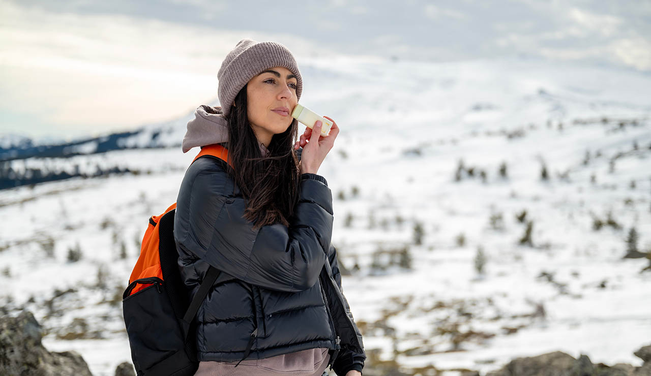 Mujer echándose crema en la nieve