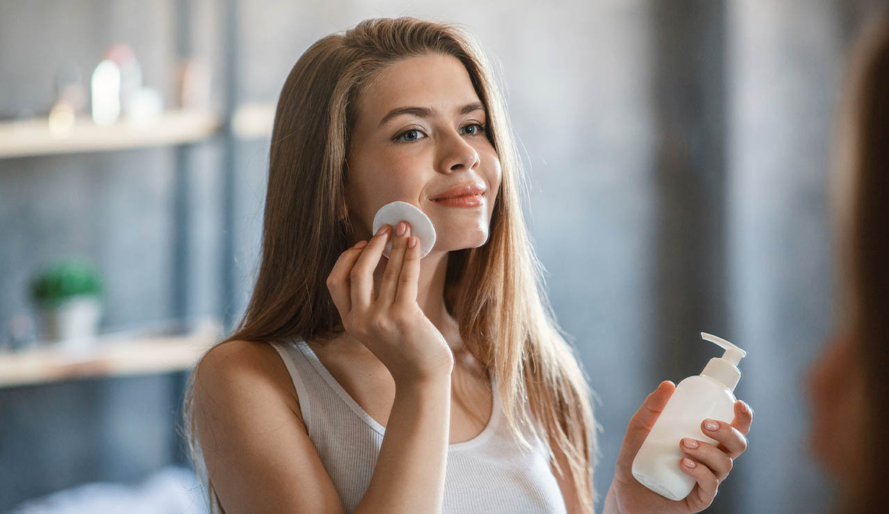 Mujer desmaquilándose con un disco de algodón