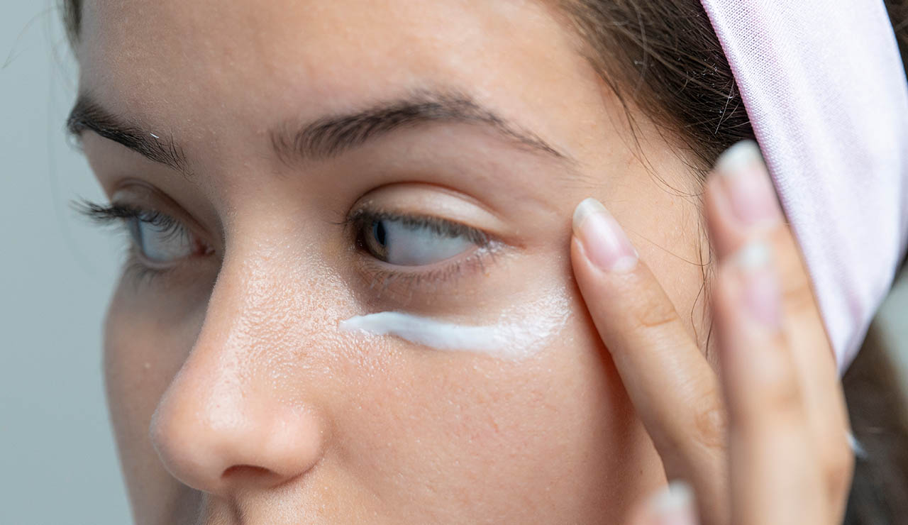 Mujer con crema para las hemorroides en las ojeras