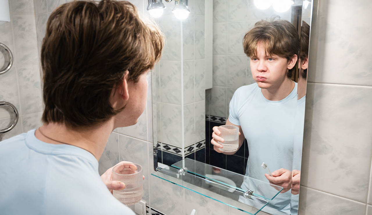 Joven enjuagándose la boca con agua oxigenada