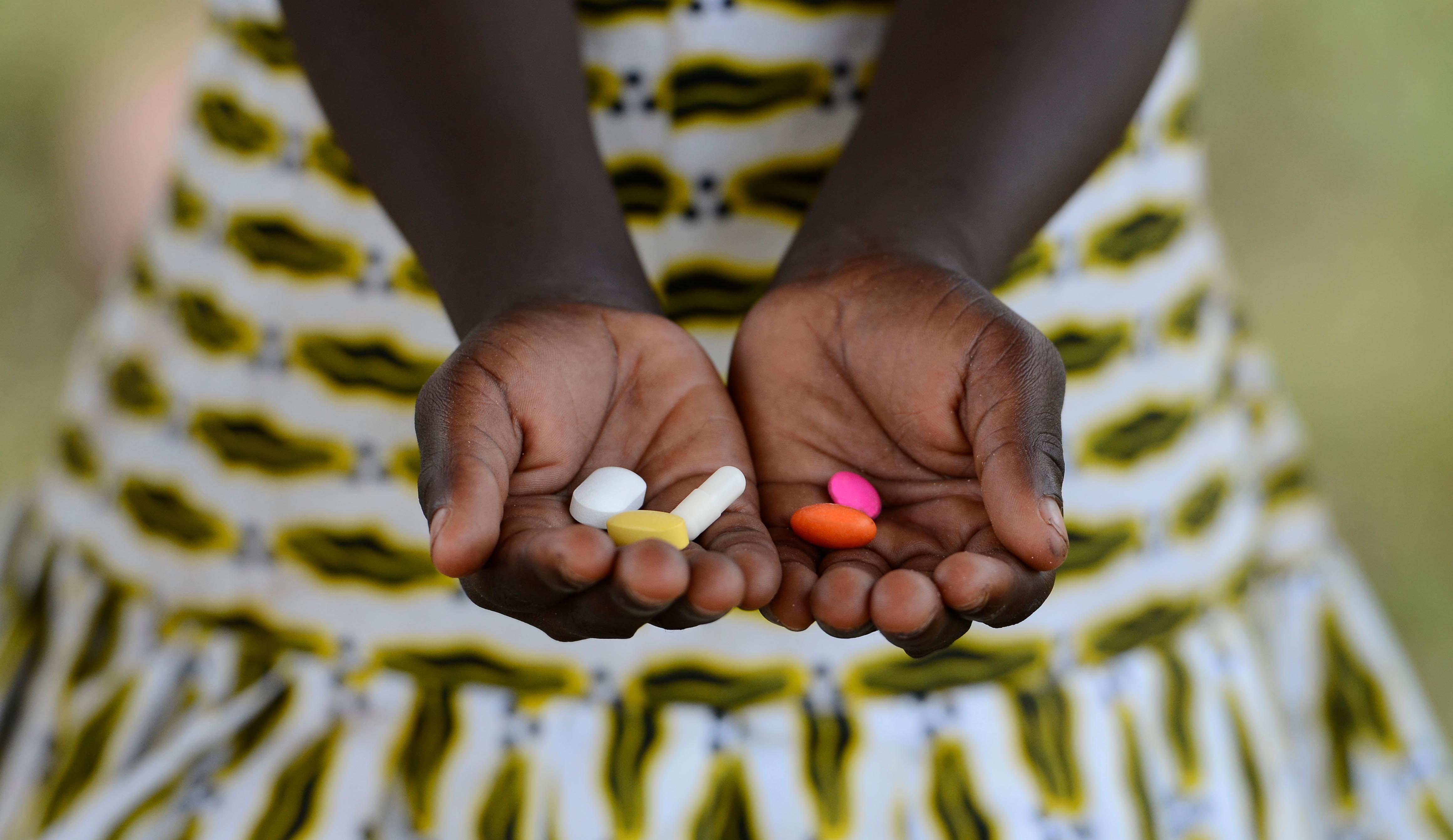 Mujer africana sosteniendo pastillas antibióticas