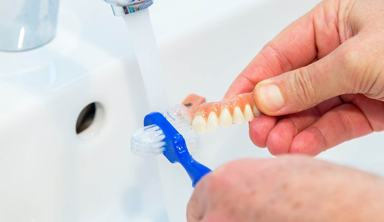 persona limpiando la prótesis dental