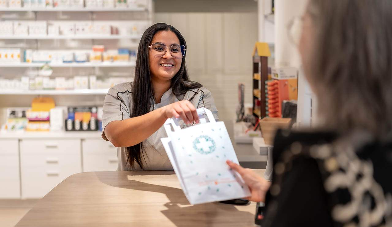Farmacéutica entregando una bolsa de papel