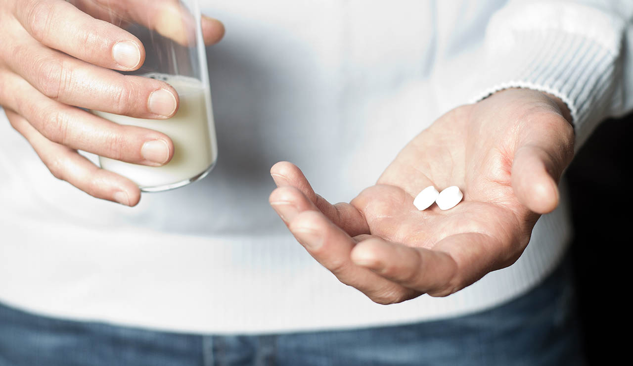 Persona con vaso de leche y antibióticos